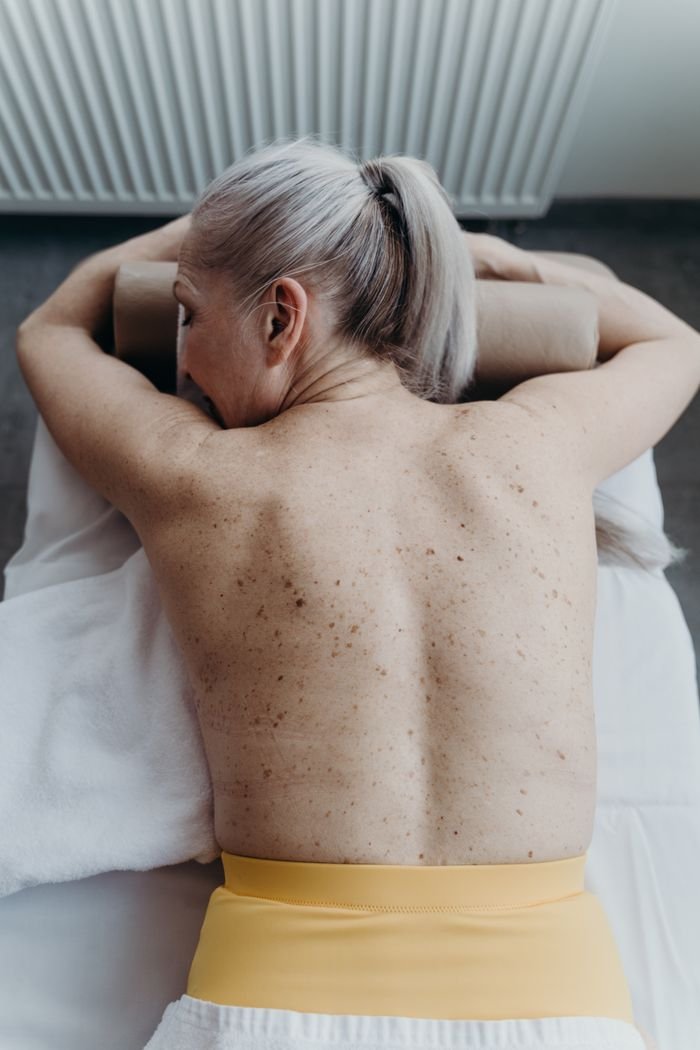 Crafting Captivating Headlines: Your awesome post title goes here Senior woman with gray hair lying topless in spa, embracing relaxation.